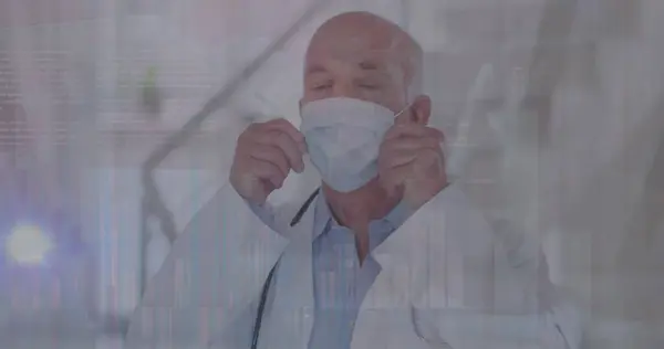 Image of data processing over caucasian male doctor with face mask. global medicine and data processing during covid 19 pandemic concept digitally generated image.
