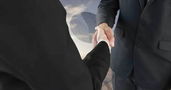 Close up of a handshake between businessmen with a background of a wide open field. Digital image of graphs an statistics are running on the background