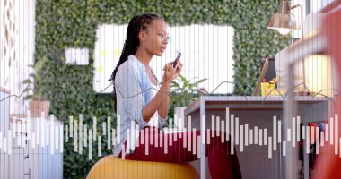 Ofiste akıllı telefondan konuşan çift ırklı iş kadınının görüntüsü ve diyagramı. Küresel iş, teknoloji ve dijital arayüz kavramı dijital olarak oluşturulmuş görüntü.