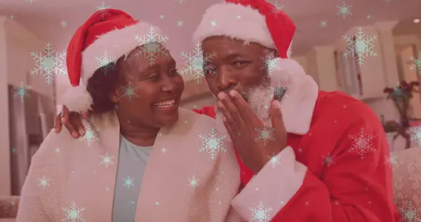 サンタの帽子をかぶって手を振るうカップルの笑顔の上に落ちる雪のイメージ クリスマス お祝いのコンセプトデジタル生成画像 — ストック写真