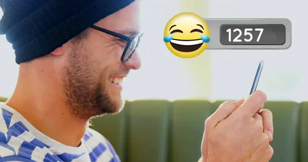 Close up side view of handsome Caucasian man laughing while typing on mobile phone. image of laughing emoji with number count up on the foreground