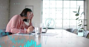 Ofiste dizüstü bilgisayar kullanarak Asyalı iş kadınının enerji simgelerinin canlandırılması ve grafik işlemleri. Çalışma, bağlantı, iş, veri, dijital arayüz ve iletişim, dijital olarak oluşturulmuş video.