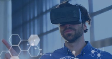 Bilimsel verilerin ön planda beyaz bir görüntüsü. Kafkasyalı genç bir adam, VR kulaklık takıyor. Arkaplanda etrafa bakıyor ve gülümsüyor.