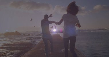 Deniz kenarındaki kayalıklarda koşan Afrikalı Amerikalı bir çiftin dikiz aynasından parlak bir ışık. Aşk ve ilişki kavramı