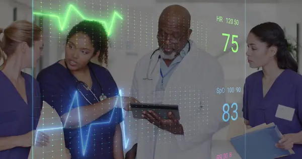 Image of cardiograph over diverse doctors working at hospital. Medicine, healthcare and digital interface concept concept digitally generated image.