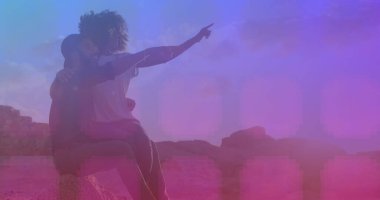 Pembe kare desenli Afro-Amerikan çift üzerinde kayaların üzerinde oturan bir yönü işaret ediyor. Aşk ve ilişki kavramı