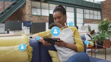 Ofiste tablet kullanan iki ırklı iş kadınının üzerindeki ikonlarla olan bağlantıların animasyonu. İş ve dijital arayüz kavramı dijital olarak oluşturulmuş video.