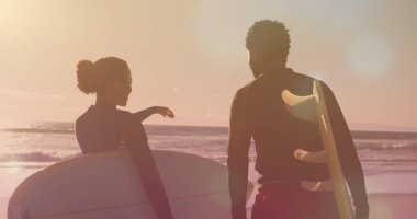 Sahilde sörf tahtası olan Afrikalı Amerikalı bir çiftin üzerindeki ışık lekeleri. moda ve yaşam tarzı kavramı dijital olarak oluşturulmuş görüntü.