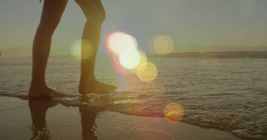 Kumsalda yürüyen beyaz bir kadının üzerindeki ışık lekeleri. yürüyüş günü ve dijital olarak oluşturulan görüntü konsepti.