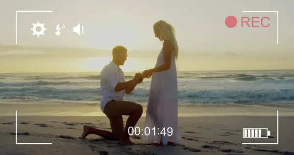 一个年轻的白人男子向一个年轻的白人女子求婚的图像 在带图标和定时器的数码摄像机屏幕上可以看到 — 图库照片