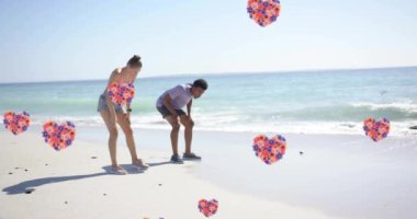 Yazın kumsalda birbirini seven farklı çiftlerin üzerinde hareket eden kalplerin animasyonu. Aşk, romantizm, sevgililer günü ve tatil konsepti, dijital olarak oluşturulmuş video.