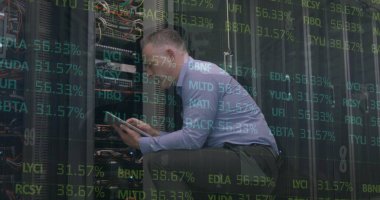 Sunucu odasında dijital tabletle çalışan beyaz erkek mühendis üzerinde borsa verileri işleniyor. Küresel finans ve iş veri depolama teknolojisi kavramı,