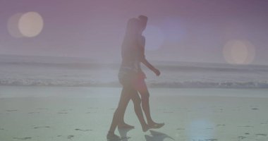 Güneşli bir günde plajda yürüyen beyaz tenli bir çiftin üzerindeki ışıklı mercek görüntüsü. Dijital bileşim, aşk, birliktelik, deniz, tatiller, aydınlanma, doğa ve keyif kavramı.