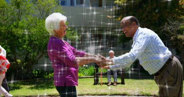 Image of light spots over diverse senior friends dancing. National dance day and digital interface concept digitally generated image.