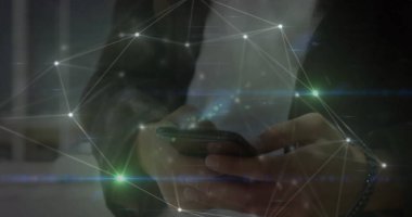 Akıllı telefonu tutan melez genç adam, ekrana odaklanıyor. Koyu renk kıyafetler giyiyor, dijital ağla etkileşime geçiyor.