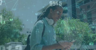 Çift ırklı erkek iş arkadaşı yürüyor, akıllı telefon kullanıyor, kot gömlek giyiyor. Uzun, sırtı bağlı saçlar ekrana odaklanıyor, sohbete daldı.