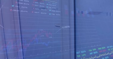 Beyaz erkek başrol oyuncusu, 51 yaşında, resmi takım elbise giyiyor, ekrandaki mali grafikleri inceliyor. İfadesi odaklanmayı ve düşünmeyi gösteriyor, görevle olan derin bağını yansıtıyor.