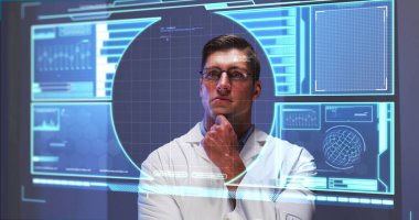 Gözlüklü beyaz erkek şef fütüristik ekranla etkileşime geçiyor. Saydam dijital ekrandaki verilere dokunuyor ve onları analiz ediyor.