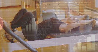 Beyaz kadın siyah spor giysisi giyiyor, pilates reformu eğitimi alıyor. Uzun kahverengi saçları ve açık teniyle egzersizine odaklanmış, formunu koruyor.