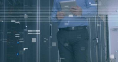 Beyaz, orta yaşlı bir adam elinde tablet, ofisinde yürüyor. Mavi gömlekli ve koyu renk pantolonlu, ekrana odaklanmış.