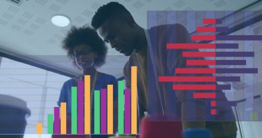 Afrikalı Amerikalı erkek ve çift ırklı kadın profesyoneller mali verileri inceliyor. Her ikisi de iş kıyafeti giyiyorlar ve bir tablette gösterilen renkli grafiklere odaklanıyorlar.