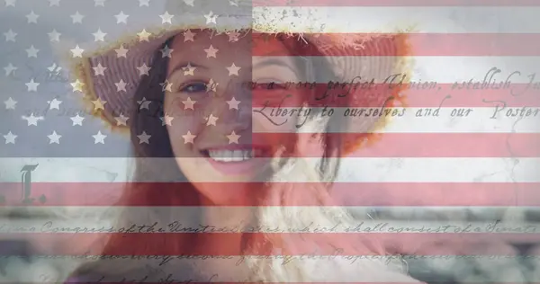 stock image Constitution text and american flag against portrait of caucasian woman smiling in background. american independence and celebration concept