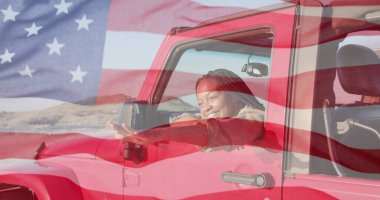 Afro-Amerikan bir kadının arabasında otururken çekilmiş Amerikan bayrağı. Vatanseverlik ve kutlama kavramı dijital olarak oluşturulmuş imaj.