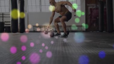 Kettlebells kaldırmak, gömleksiz bir adam renkli Bokeh ışıkları animasyonunda egzersiz yapıyor. Spor, güç, egzersiz, vücut geliştirme, ağırlık geliştirme