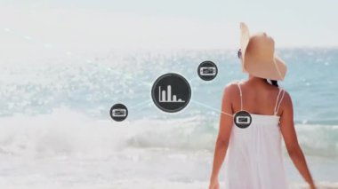Kumsaldaki beyaz kadın üzerindeki grafik simgeleriyle bağlantılı ağların animasyonu. Genel tatil, bağlantılar, hesaplama ve veri işleme kavramı dijital olarak oluşturulmuş video.