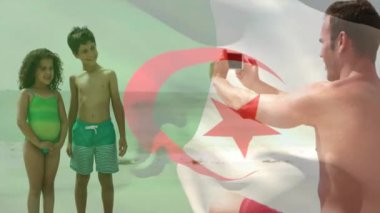 Kafkas ailesinin sahilde fotoğraf çekmesi üzerine Cezayir bayrağının animasyonu. Vatanseverlik, aile ve dijital arayüz kavramı dijital olarak oluşturulmuş video.