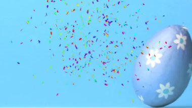 Mavi arka planda paskalya yumurtası üzerine düşen konfeti animasyonu. Paskalya, gelenek, din ve inanç konsepti dijital olarak oluşturulmuş video.