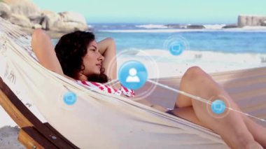 Sahilde hamakta yatan melez bir kadının üzerindeki ikonlarla olan bağlantıların animasyonu. Küresel bağlantılar, tatiller, yaz, yaşam tarzı ve dijital arayüz kavramı dijital olarak oluşturulmuş video.