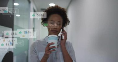 Akıllı telefon kullanan Afro-Amerikan iş kadınlarının ikon ve numaralarının animasyonu. Küresel ağ, iş, bağlantılar, hesaplama ve veri işleme kavramı dijital olarak oluşturulmuş video.