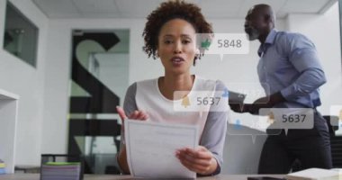 Afro-Amerikan iş kadınının ofisindeki ikon ve numaraların animasyonu. Küresel ağ, iş, bağlantılar, hesaplama ve veri işleme kavramı dijital olarak oluşturulmuş video.