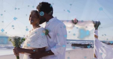 Kumsalda, sosyal medya simgeleriyle kucaklaşan ve onlara ağ animasyonu yapan bir çift. Romantizm, dijital, bağlantı, teknoloji, ağ, ilişki