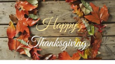 Ahşap arka planda sonbahar yaprakları üzerinde mutlu şükran günü metinlerinin animasyonu. Amerikan geleneği, şenlik, kutlama ve gelenek konsepti dijital olarak oluşturulmuş video.