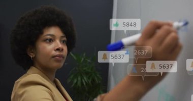 Afro-Amerikan iş kadınının ofisinde yazdığı resimlerin ve numaraların animasyonu. Küresel ağ, iş, bağlantılar, hesaplama ve veri işleme kavramı dijital olarak oluşturulmuş video.