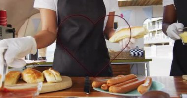 Sosisli hazırlamak, önlüklü, yiyecekten sonra kalp animasyonu yapan insanlar. Yemek pişirme, yemek hazırlama, kalp şekli, animasyon, aşçılık, takım çalışması