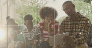 Aile kanepede oturuyor, tabletin tadını çıkarıyor, yıldızlı gökyüzü animasyonu ile örtülü. Bağlanma, teknoloji, eğlence, gece, yıldızlar, rahatlama