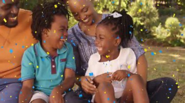 Gülümseyen aile üzerine konfeti animasyonu açık havada oturup anın tadını çıkarıyor. Mutluluk, kutlama, bağlılık, birliktelik, şenlik, neşe