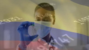 Kolombiya bayrağının Afrika kökenli Amerikalı kadın doktor üzerinde aşılanmış bir maske ile canlandırılması. Küresel tıp, bağlantılar, hesaplama ve veri işleme kavramı, dijital olarak oluşturulmuş video.