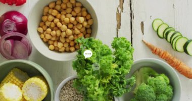 Taze sebzeler ve beyaz ahşap masanın üzerinde sohbet baloncuğu animasyonu olan nohutlar. Sağlıklı beslenme, vejetaryen, beslenme, malzemeler, vegan, yemek pişirme konsepti