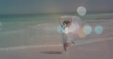 Sahilde koşan, atkılı bir kadın renkli bir bokeh animasyonunun üzerinde. Macera, rahatlama, tatil, özgürlük, doğa, fitness