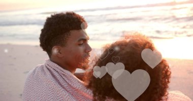 Yazın kumsalda birbirini kucaklayan farklı çiftler üzerinde hareket eden kalplerin görüntüsü. Aşk, romantizm, sevgililer günü ve tatil konsepti dijital olarak oluşturulmuş imaj.
