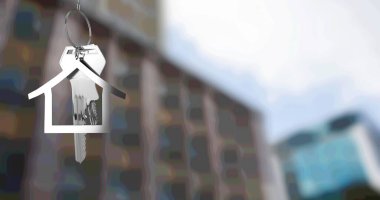 Bulanık şehir binasının önünde asılı gümüş ev anahtarlığı ve anahtarı. gayrimenkul işi, ev ve finans kavramı dijital olarak üretilen imaj.