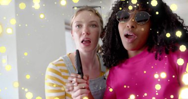 İki farklı genç kızın uzaktan kumandayla şarkı söylemesini gösteren sarı ışıklar. Arkadaşlık, gençlik, boş zaman, eğlence, müzik, hafta sonu ve yaşam tarzı, dijital olarak oluşturulmuş görüntü.