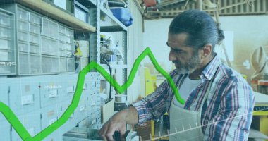 Olgun beyaz erkek marangozun atölyedeki yeşil grafik üzerinde işlem yaparken görüntüsü. Bağlantı, ağ, veri, küçük işletme, zanaat ve marangozluk, dijital olarak oluşturulmuş görüntü.