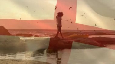 Sahilde yürüyen Afro-Amerikan bir çift üzerinde İngiliz bayrağının canlandırılması. Bayraklar, ülkeler, vatanseverlik ve yaşam tarzı konsepti, dijital olarak oluşturulmuş video.