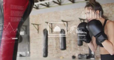 Spor salonunda beyaz bir kadının boks torbasını yumruklaması üzerine yapılan çizimler ve veri işleme animasyonları. Teknoloji, spor ve dijital arayüz kavramı, dijital olarak üretilen video.