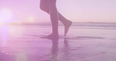 Sahilde yürüyen melez bir kadının üzerindeki ışık lekelerinin canlandırması. Spor, doğa ve dijital arayüz konsepti dijital olarak oluşturulmuş video.